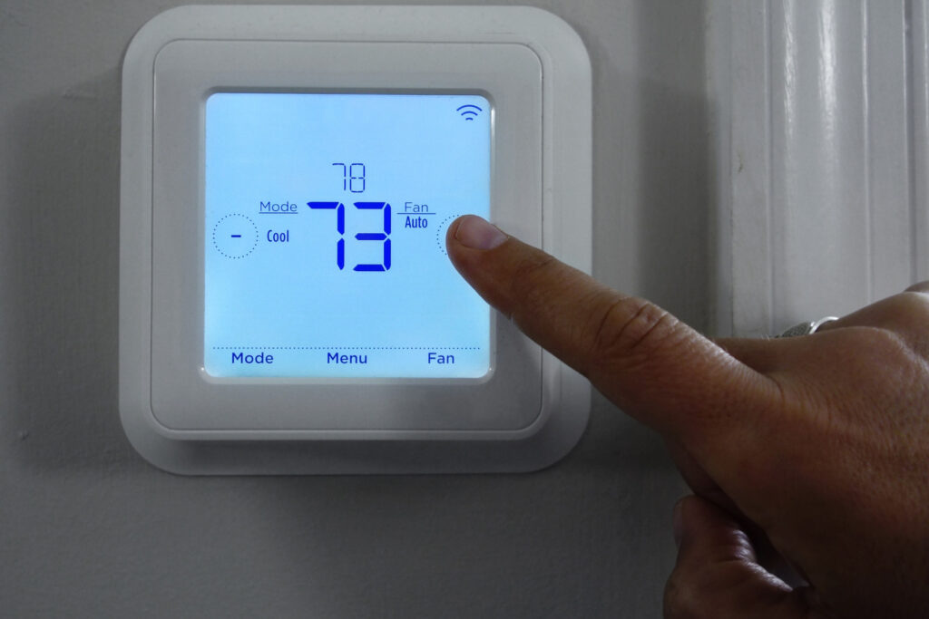 Living a Smart and Upscale Lifestyle - Wi-Fi-enabled thermostat being operated by a man